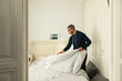 © BONNINSTUDIO/Stocksy - Latin man making bed at home.