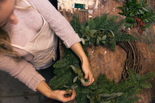 Woman's Hands Making A Holiday Wreath In Work Shop.