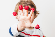 Cute Child With Raspberries On The Fingers