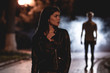 © Artem - The woman stand on a dark street on a background of the man in fume. night time
