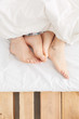 © Miquel Llonch/Stocksy - Close up of feet in a young couple bed