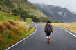 © 365mm/Stocksy - Back view of backpacker walking down the remote road