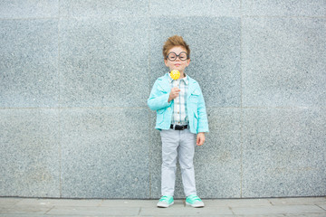 Wall Mural - Fashion kid with lollipop near gray wall