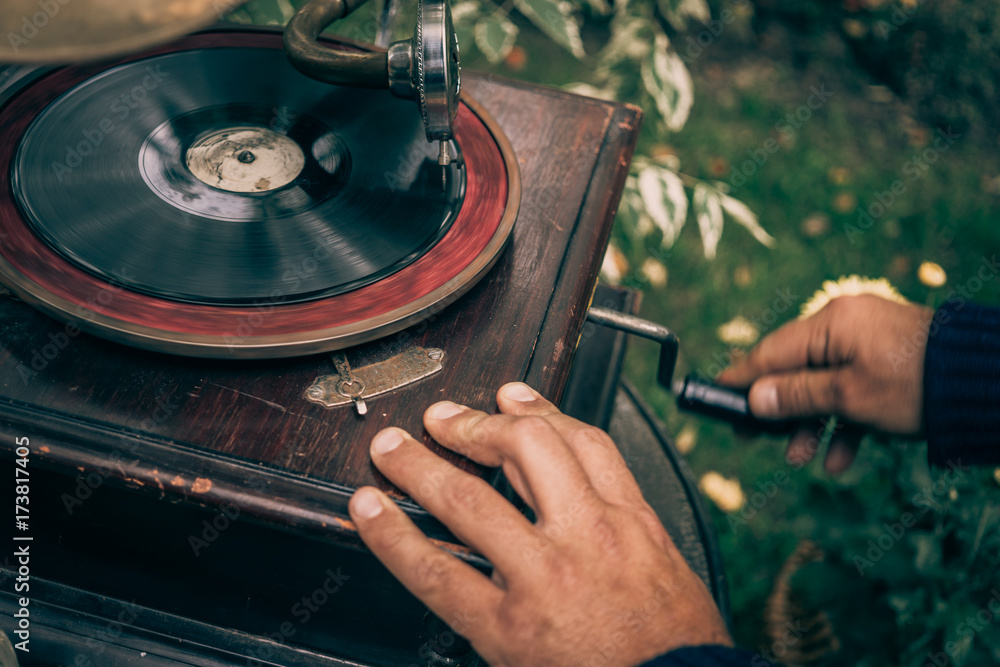 Obraz na płótnie Man twists a pen on a vintage gramophone to play music, retro toned w salonie