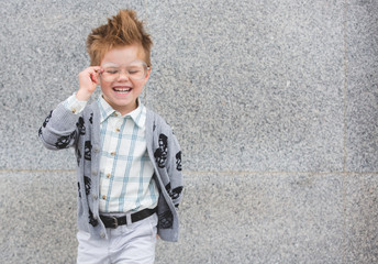 Wall Mural - Fashion kid with glasses near gray wall