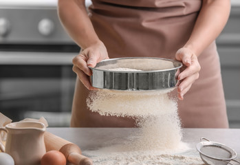 Wall Mural - Female chef sifting flour onto kitchen table