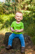 © justesfir - Little boy sitting on a stump in park in summer