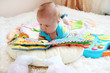 Cute little baby reading a boog among toys