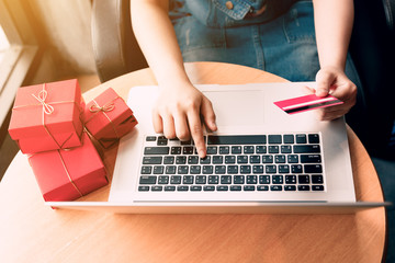 Top view of woman hand holding credit card and doing shopping online near window at home.