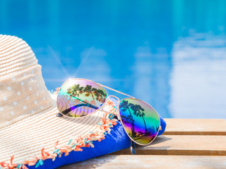 Wall Mural - Beach hat, sunglasses, blue towel and sunscreen at the side of swimming pool. Vacation, beach, summer travel concept