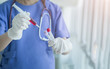 © chompoo - Soft focus hand in a glove of a nurse,doctor put blood in syringe to test tube in color tone in the hospital.