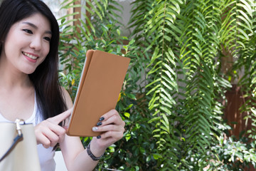 asian woman sit at outdoor cafe. young female adult use digital tablet at coffee shop. happy teenager connect online network communication. technology, lifestyle concept