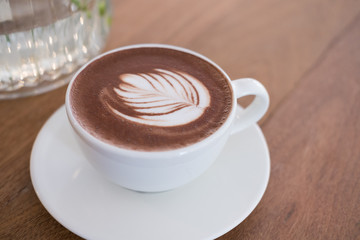 hot chocolate drink with leaf latte art. cocoa beverage on wood table.