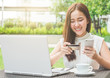 © Nattakorn - Young beautiful Asian woman using credit card and laptop for online shopping at outdoor park, smile/fresh and happy feeling in the morning, freelancer businesswoman lifestyle concept