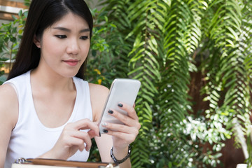 asian woman sit at outdoor cafe. young female adult use mobile phone at coffee shop. attractive teenager connect online network communication on smart phone. technology, lifestyle concept