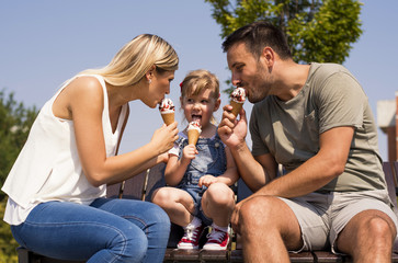 Parents and kid eating ice cream and having fun outside