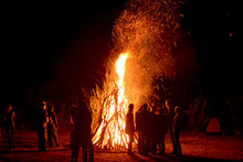 People Stand Near A Big Fire At Night