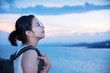 © eggeeggjiew - Asian backpacker woman breathing fresh air on sea and sunset sky background.