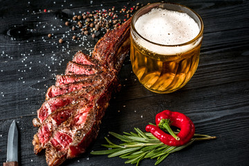 Grilled steak seasoned with spices and fresh herbs served with mug of beer, fresh red pepper