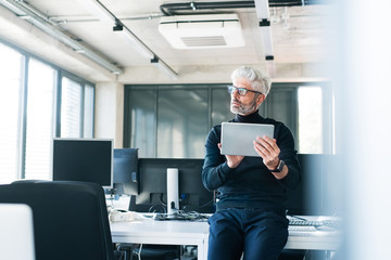 Wall Mural - Mature businessman with tablet in the office.