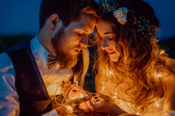 Wall Mural - Beautiful bride and groom on a meadow at night.