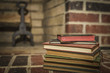stack of old vintage books in front of a brick fireplace