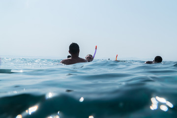 People swim on the surface of the water in masks with tubes and look at the coral reef