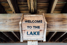 Wooden "welcome To The Lake" Sign Under Dock