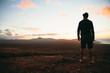 © AlejandroMCB photo & film/Stocksy - Man standing at valley and looking afar at the sea at sunset