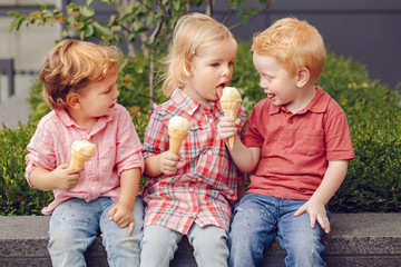 Group portrait of three white Caucasian cute adorable funny children toddlers sitting together sharing ice-cream food. Love friendship fun concept. Best friends forever.