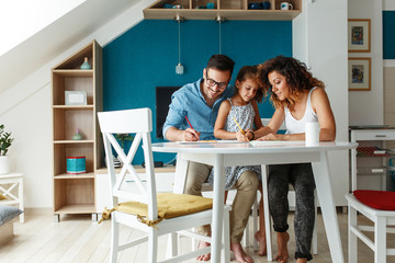 Father and mother teach daughter to draw.They sitting in living room and making fun.