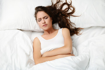 Wall Mural - Sick young woman lying in white bed