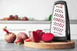 Fresh beetroot and grater on table in kitchen