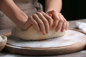 Wall Mural - Female chef kneading dough on wooden board at kitchen