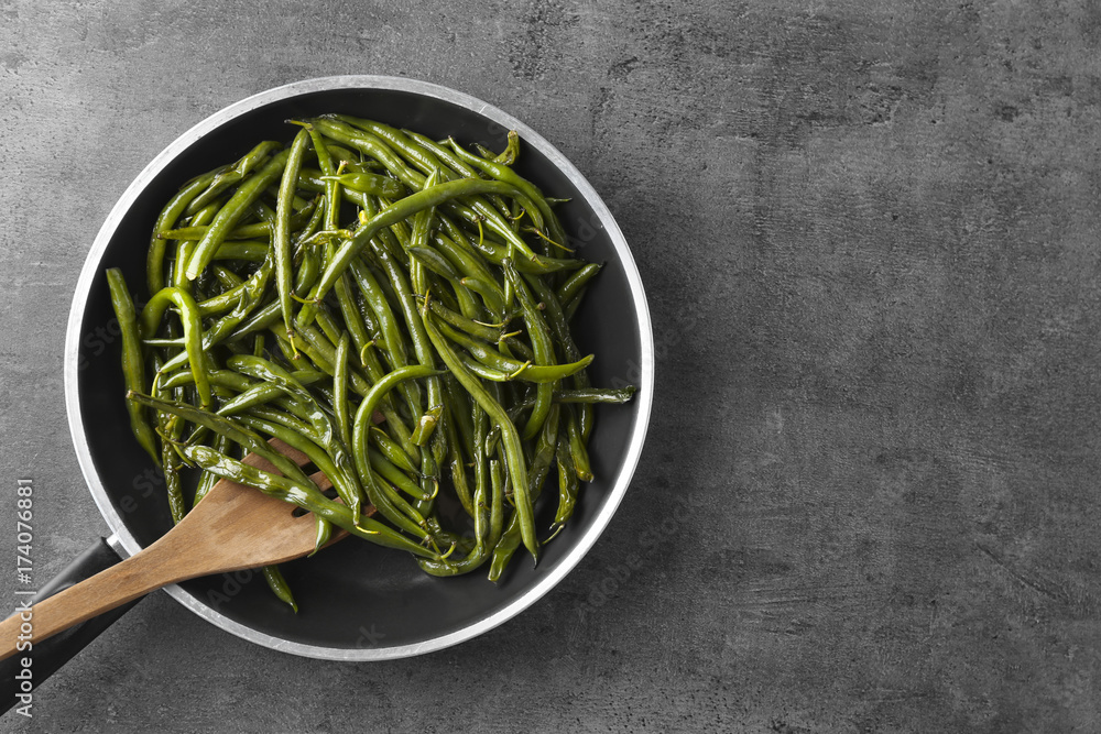 Delicious green beans in frying pan on grey background