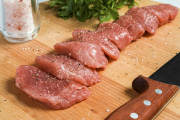 Raw meat pork tenderloin on cutting board ready to cook pork tenderloin cut into pieces of medallions marinated in salt and pepper