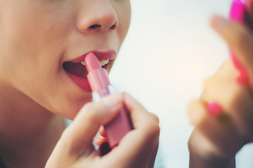 Picture of a woman's face with a lipstick on her lips.