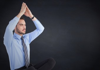 Canvas Print - Business man meditating against navy chalkboard