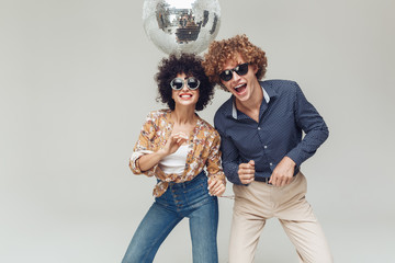 Emotional smiling retro loving couple dancing near disco ball.