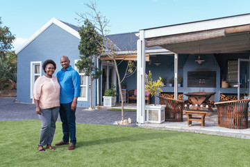 Smiling African couple standing outside on their lawn