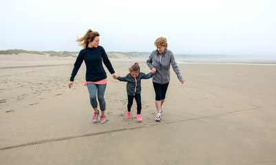 Three generations female running on the beach in autumn