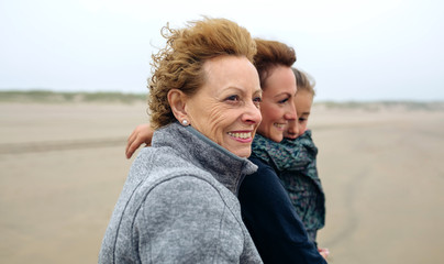 Closeup of three generations female walking on the beach in autumn