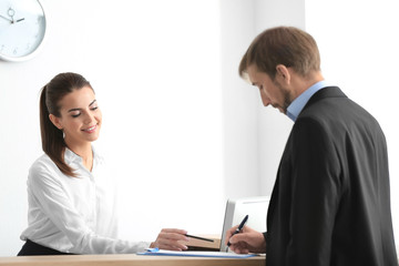 Wall Mural - Young female receptionist meeting client in office