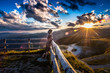 Girl leaning against the fence watching a beautiful sunset in a peaceful and tranquil place, Mount Pizzoc summit, Veneto, Italy