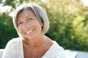 Portrait of cheerful senior woman relaxing in outdoors sofa