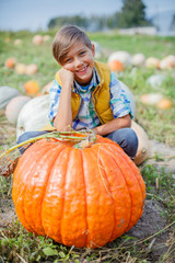boy having fun with pumpkins on pumpkin patch on farm