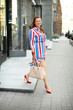 © Africa Studio - Beautiful overweight woman in bright striped dress walking on city street