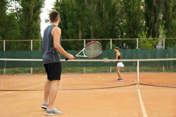 Canvas Print - Young man and woman playing tennis on court