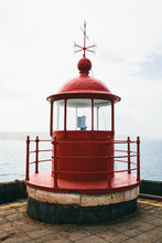 Top Of A Traditional Red Lighthouse In Front Of The Sea