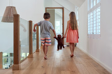 Boy And Girl Holding Hands Of Plush Teddy Bear Walking Inside House &#xA;